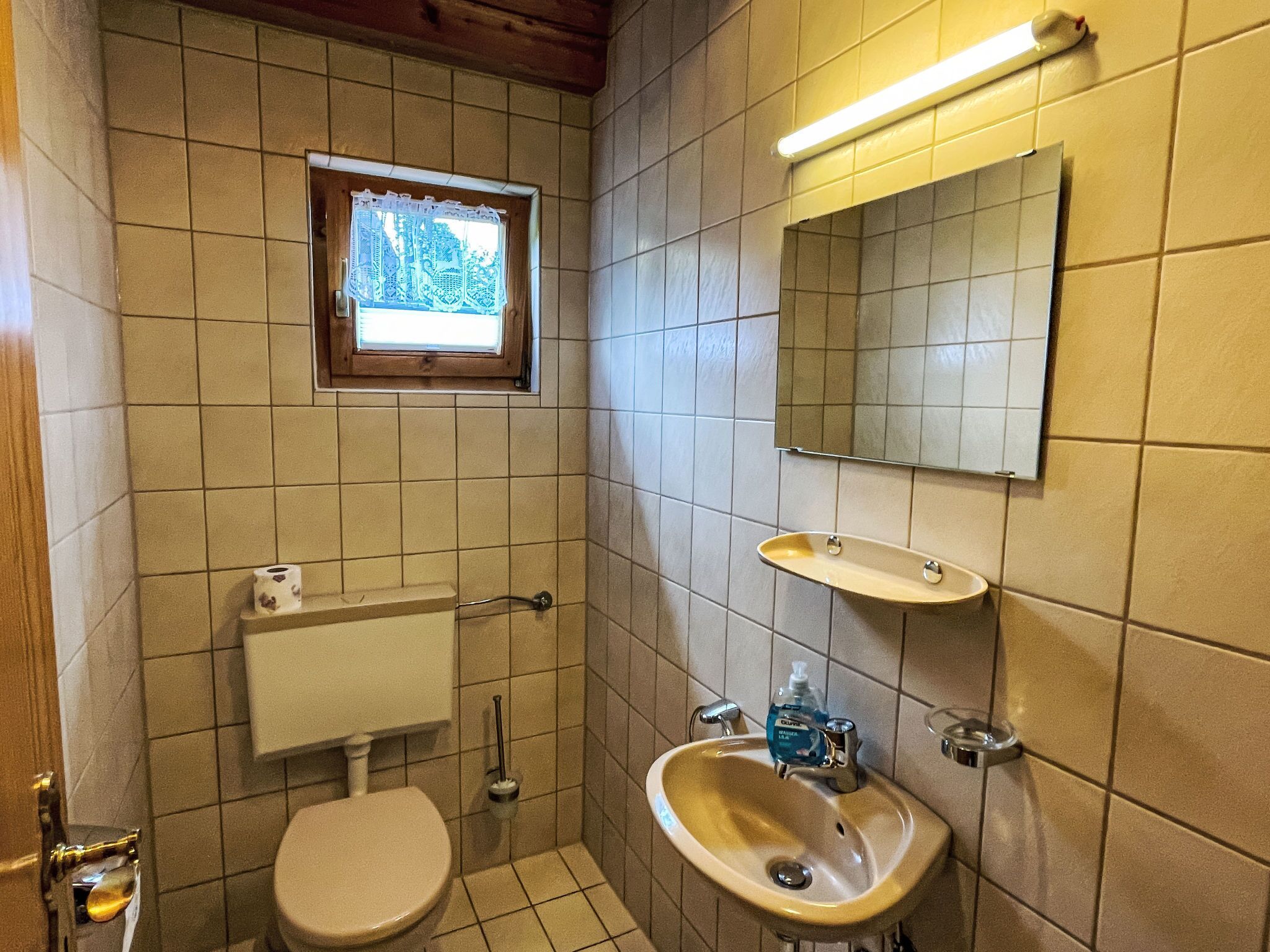 A small bathroom with a toilet, sink, and window.