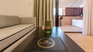 Habitación de hotel con sofá, una mesa con un logotipo y vistas al área de estar.
