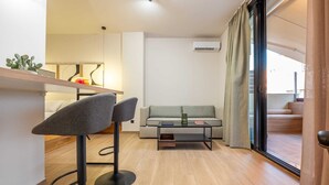 Una sala moderna con un sofá, una mesa de centro y dos taburetes de bar.