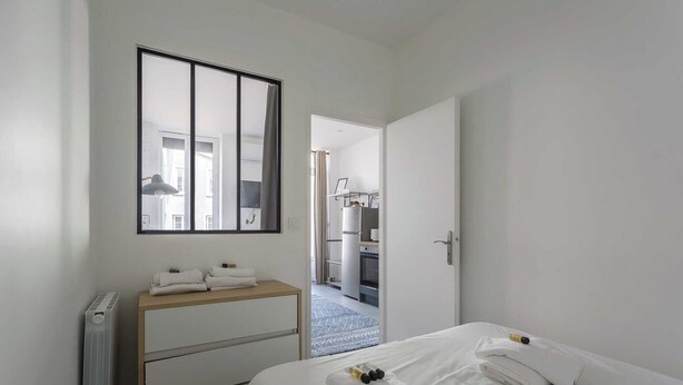 A hotel room with a bed, a bedside table with towels, a radiator, and a mirror on the wall. - DIFY Wilson - Villeurbanne (Villeurbanne)