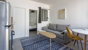 A compact living space with a kitchenette, a sofa, a dining table with chairs, and a patterned rug. - DIFY Wilson - Villeurbanne (Villeurbanne)