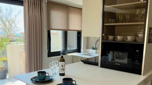 Une cuisine moderne avec un îlot central, des tabourets de bar, une bouteille de vin et un four à micro-ondes.