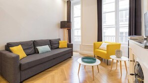A modern living room with a grey sofa, yellow armchair, and a small round table. - DIFY Lovely - Centre-ville (Lyon)