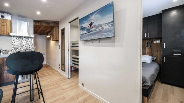 Une cuisine moderne avec un tabouret de bar noir, un plancher en bois et un tableau représentant un skieur accroché au mur.