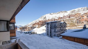 Une ville de montagne enneigée, avec des bâtiments traditionnels en bois et un hôtel moderne.