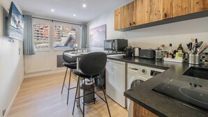 Une cuisine moderne avec des meubles en bois, un plan de travail noir et une vue sur une montagne enneigée par la fenêtre.