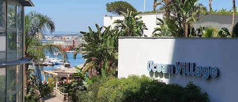 A view of Ocean Village with a clear sky, a marina with boats, and lush greenery.