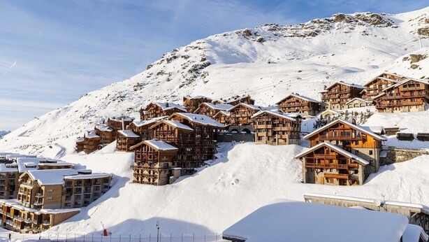 Een besneeuwde bergdorp met houten gebouwen en skipistes.