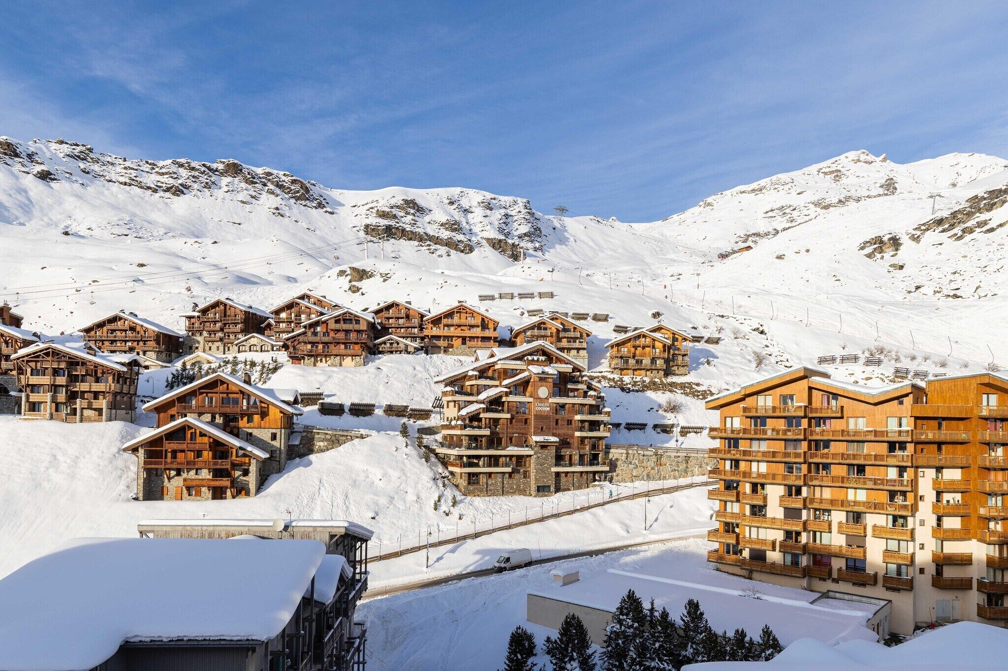 A snow-covered mountain resort with wooden buildings and a ski lift.