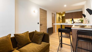 Een moderne woonkamer met een bank en een keuken op de achtergrond.