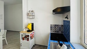 A compact kitchen with a coffee machine, a kettle, and a small cabinet. - That's Amuri - Holiday apartment (Palermo)