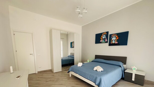 A modern bedroom with a large bed, a desk, and a wardrobe. - That's Amuri - Holiday apartment (Palermo)