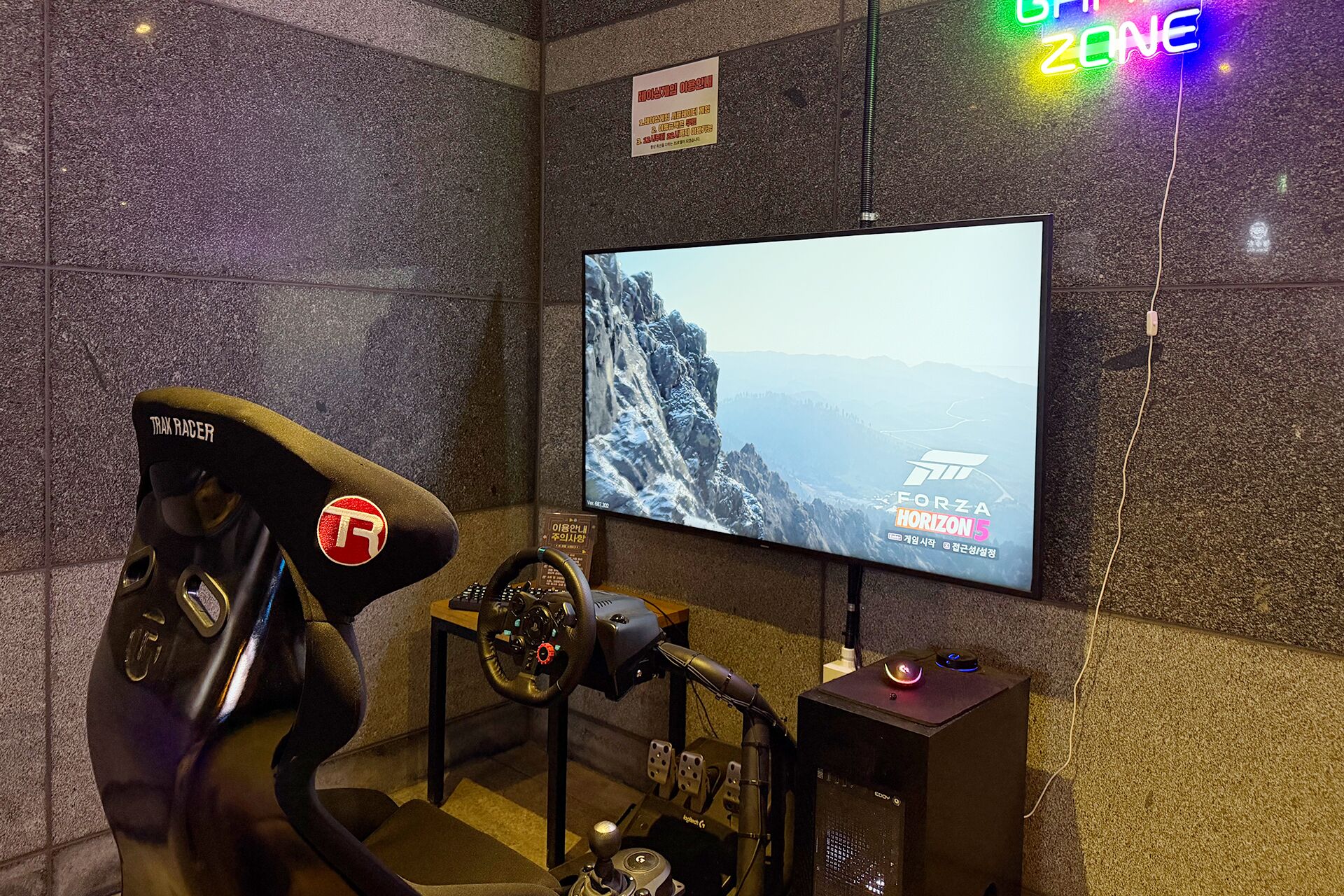 Un équipement de jeu comprenant un siège de course, un volant, des pédales et un écran affichant un jeu de course.