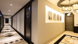 A hotel corridor with a checkered floor, a wall-mounted light fixture, and framed artwork. - 3S HOTEL DONGTAN - BOUTIQUE (Hwaseong)