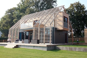 A modern house with a sloped roof, large windows, and a balcony.