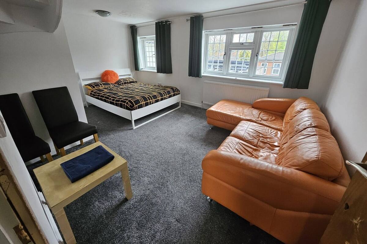 A compact room with a bed, a sofa, a chair, and a small table.
