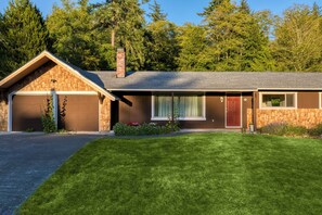 A single-story house with a garage, a front porch, and a well-maintained lawn. - Lodge at Deception Pass | Trails, Hot Tub, Walk to Cornet Bay (Oak Harbor)