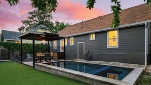 A backyard with a swimming pool, a covered patio, and a well-maintained lawn. - Casa Que Canta by AvantStay | Private Pool, Firepit & Walkable East Austin Gem (Austin)