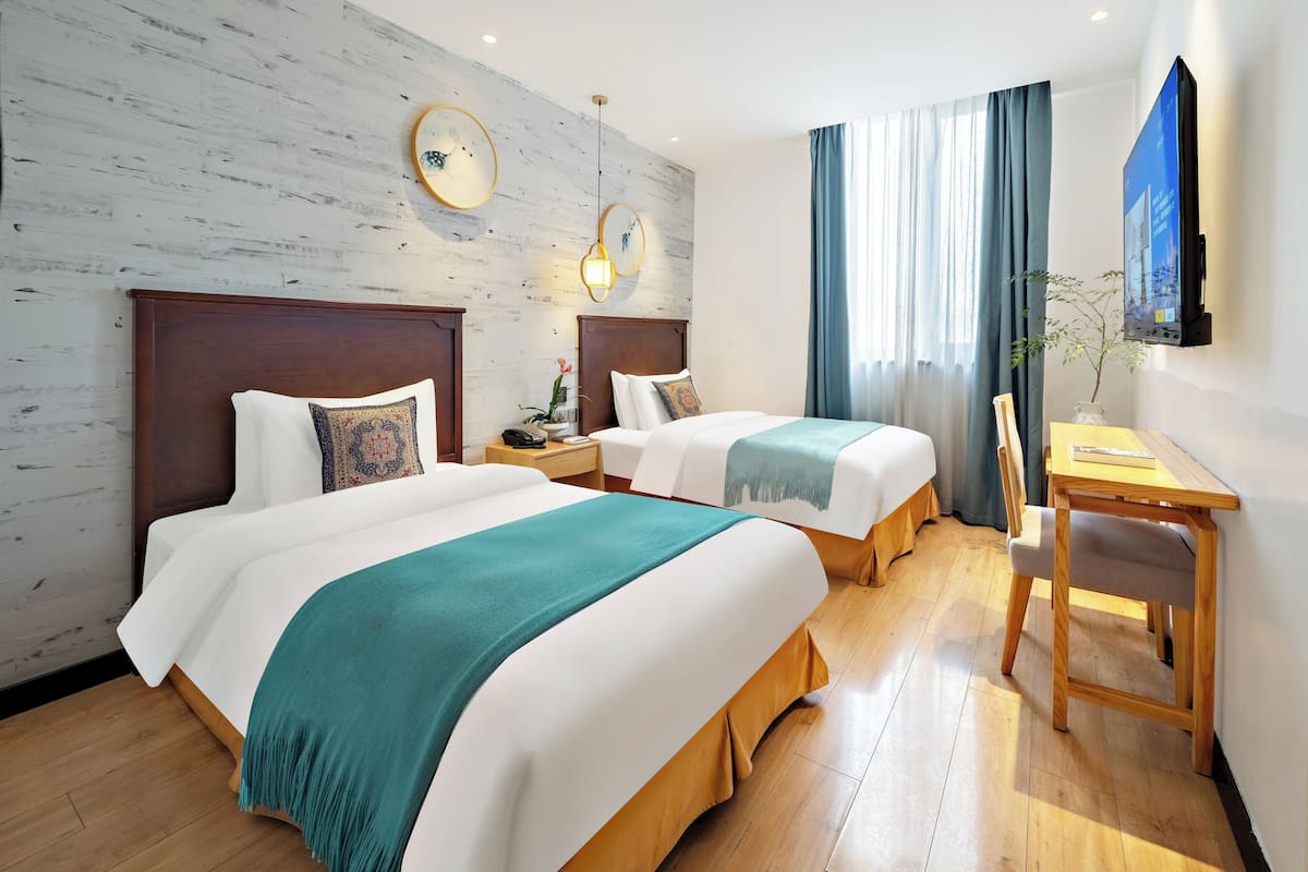 Habitación de hotel con dos camas, un escritorio y una televisión.