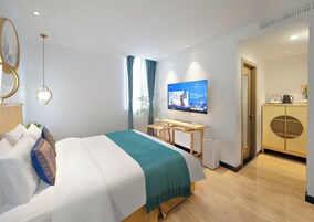 A modern hotel room with a bed, a desk, a television, and a wardrobe.