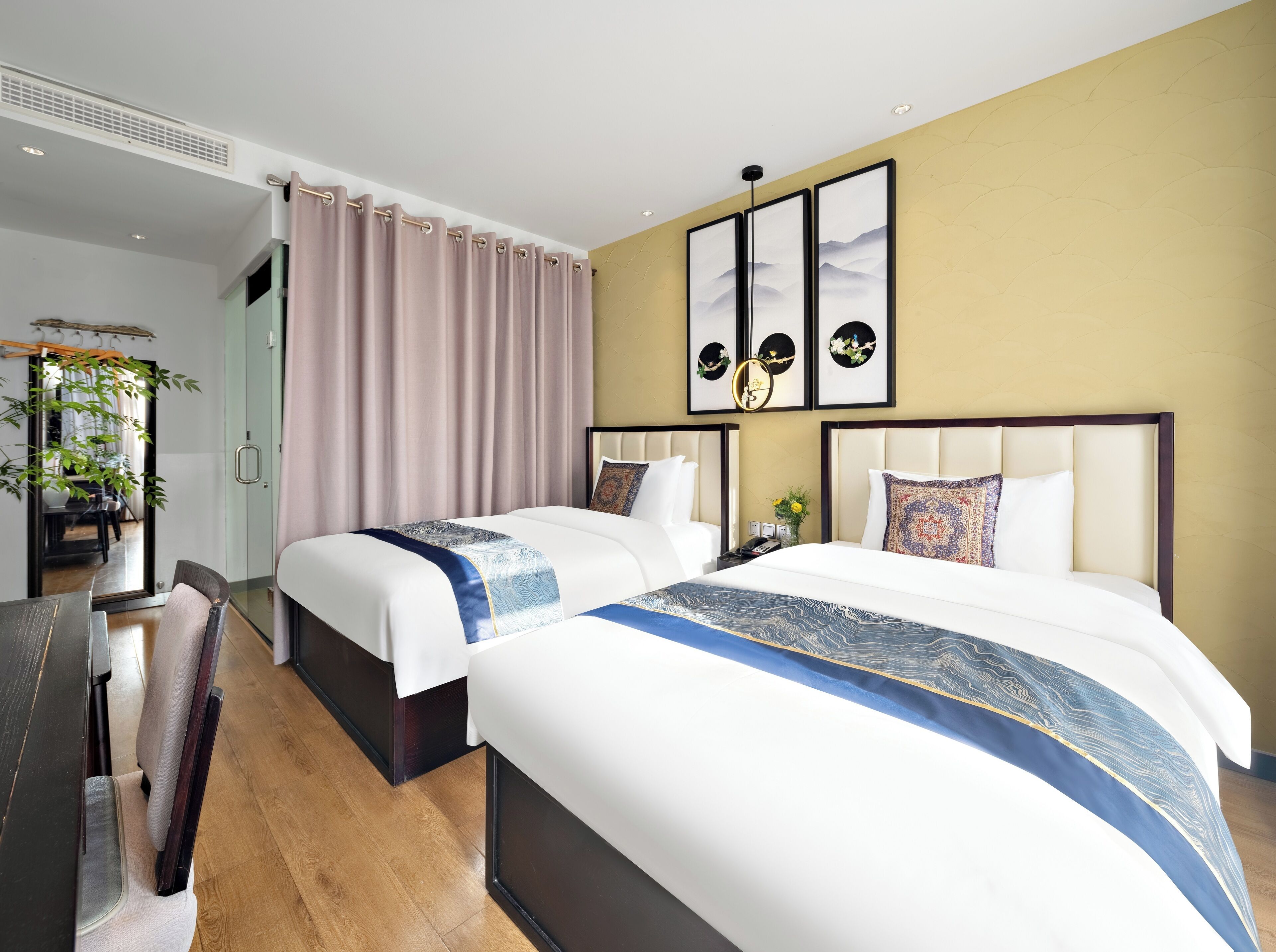 A hotel room with two beds, a desk, and a mirror.