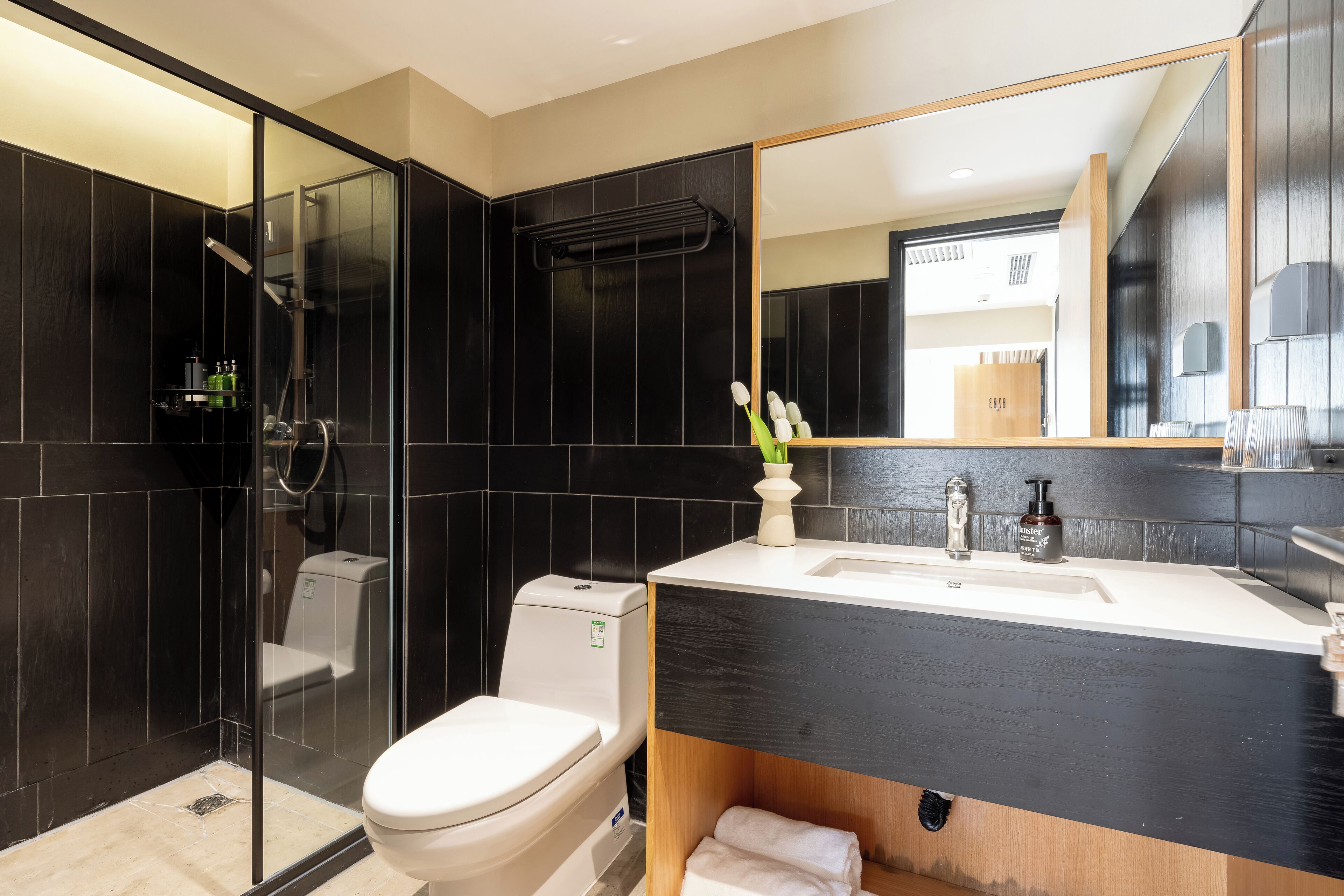 A modern bathroom with a glass-enclosed shower, a white toilet, and a vanity with a mirror.