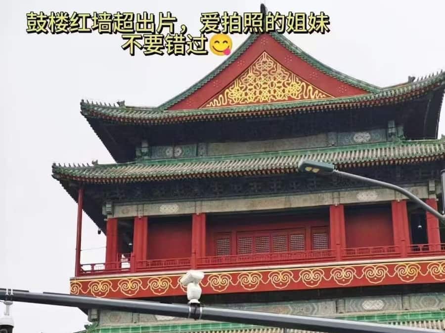 Un edificio tradicional de varios niveles, con paredes rojas y tejas de techo verdes.