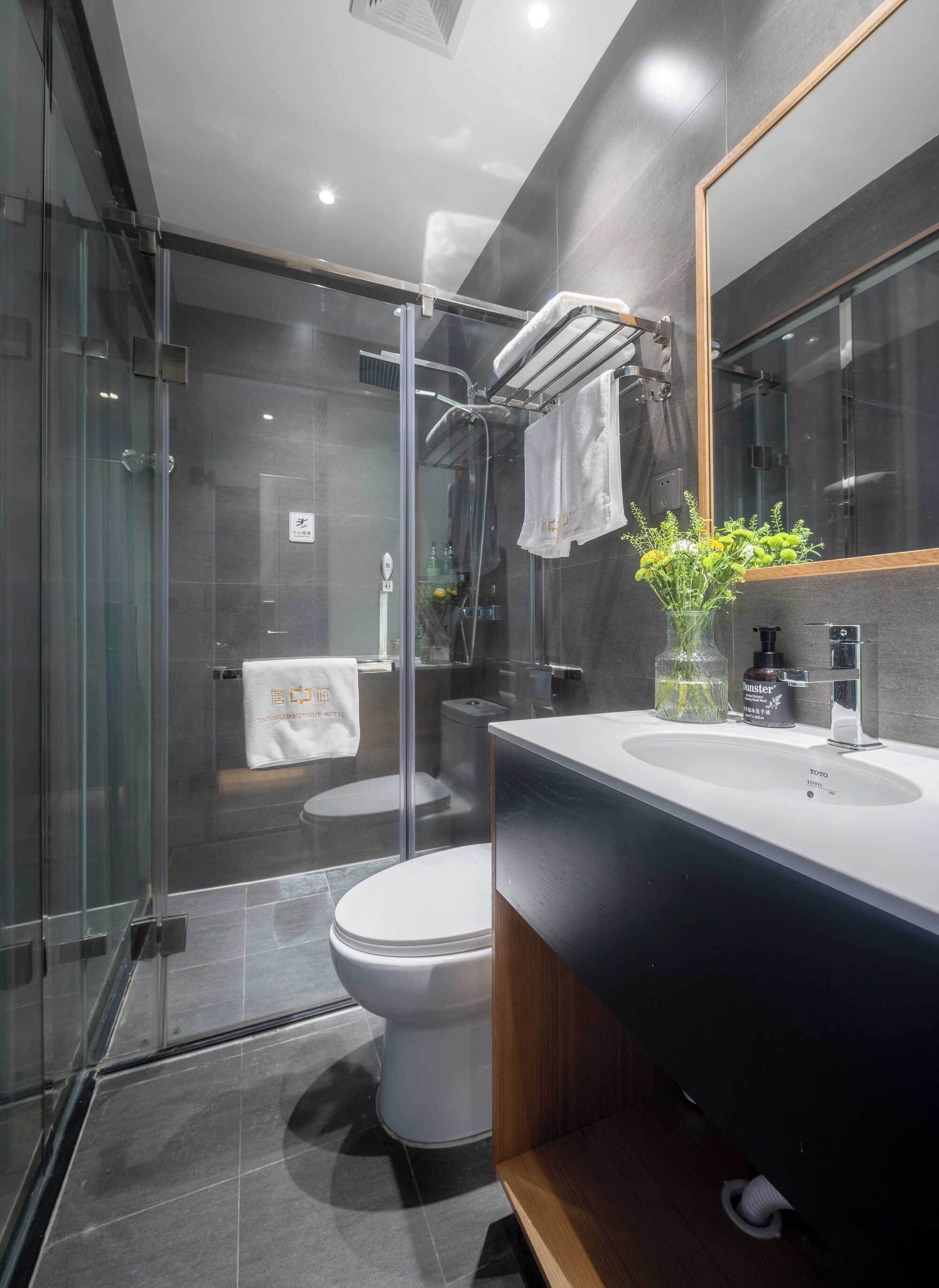 A modern bathroom with a glass shower enclosure, a white toilet, and a vanity with a black countertop.