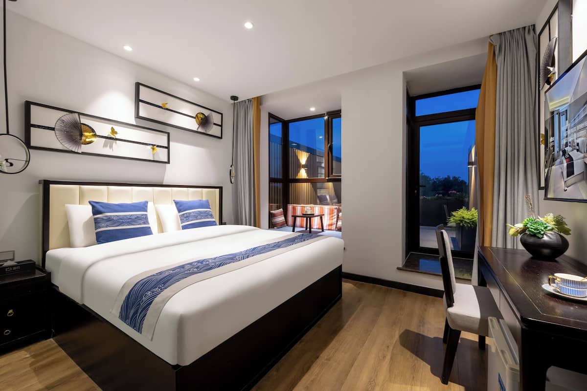 Habitación de hotel moderna con una cama grande, un escritorio y vistas al exterior.