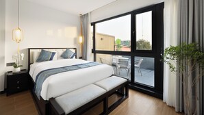 A modern hotel room with a large bed, a bedside table with a lamp, a view of the outdoor balcony, and a potted plant. - Beijing Gu Xiang 20 Hutong Culture Hotel (Beijing)