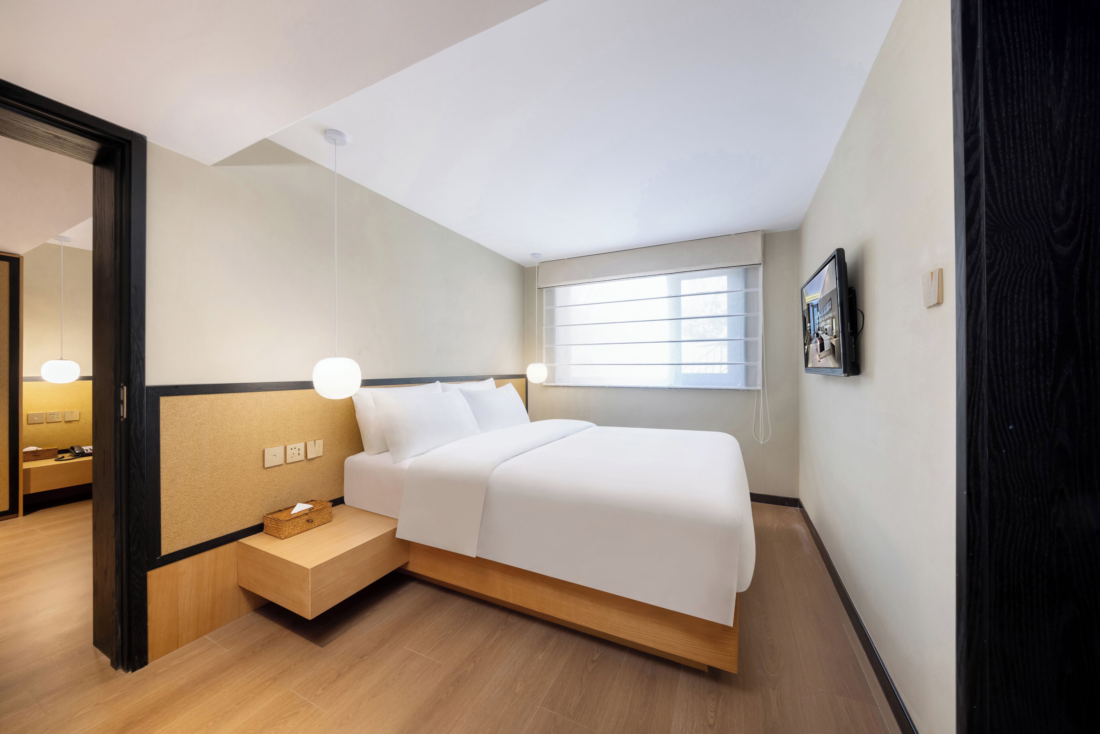 A modern bedroom with a bed, bedside table, and a window.