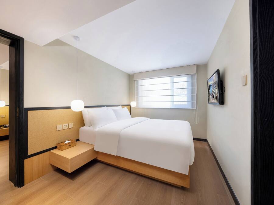 Un dormitorio moderno con cama, mesita de noche y ventana.