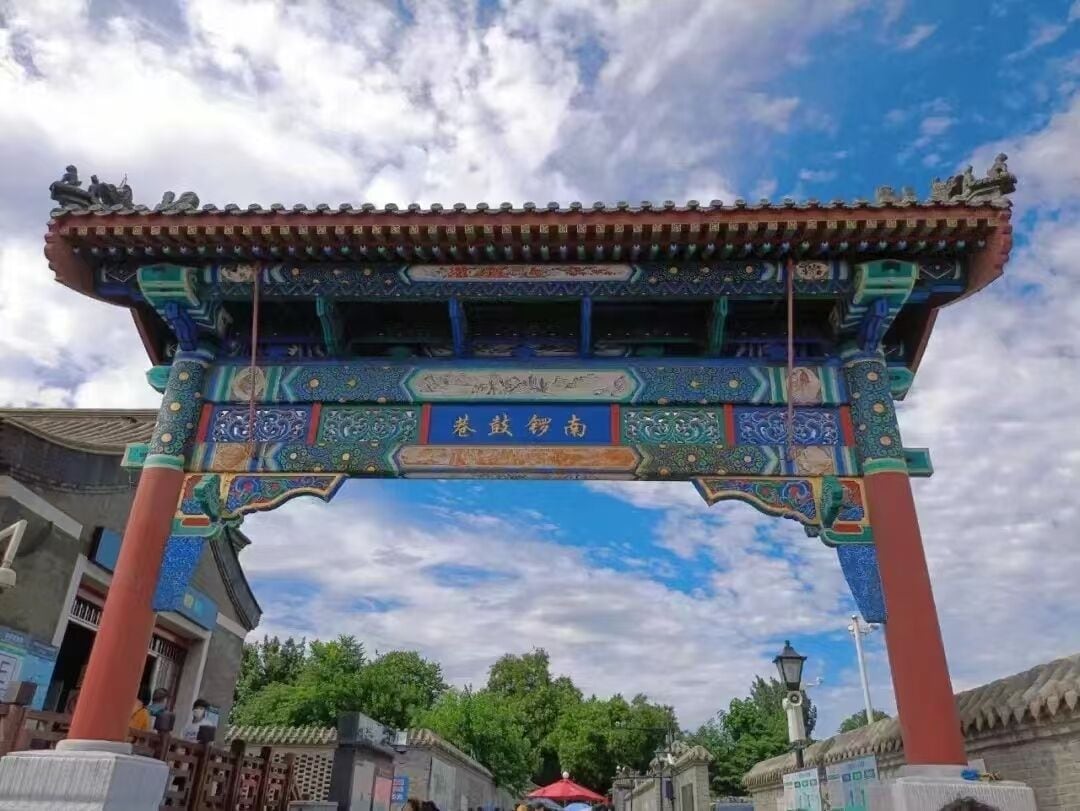 A traditional Chinese gate with intricate designs and characters, set against a clear sky.