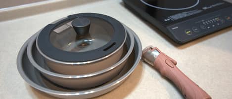 A kitchen with a stove, a pot on the stove, and a wooden handle.