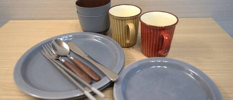 A table with two plates, a fork, a knife, and three mugs.