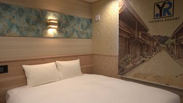 A hotel room with a bed, a wall-mounted light, and a mural of a building.