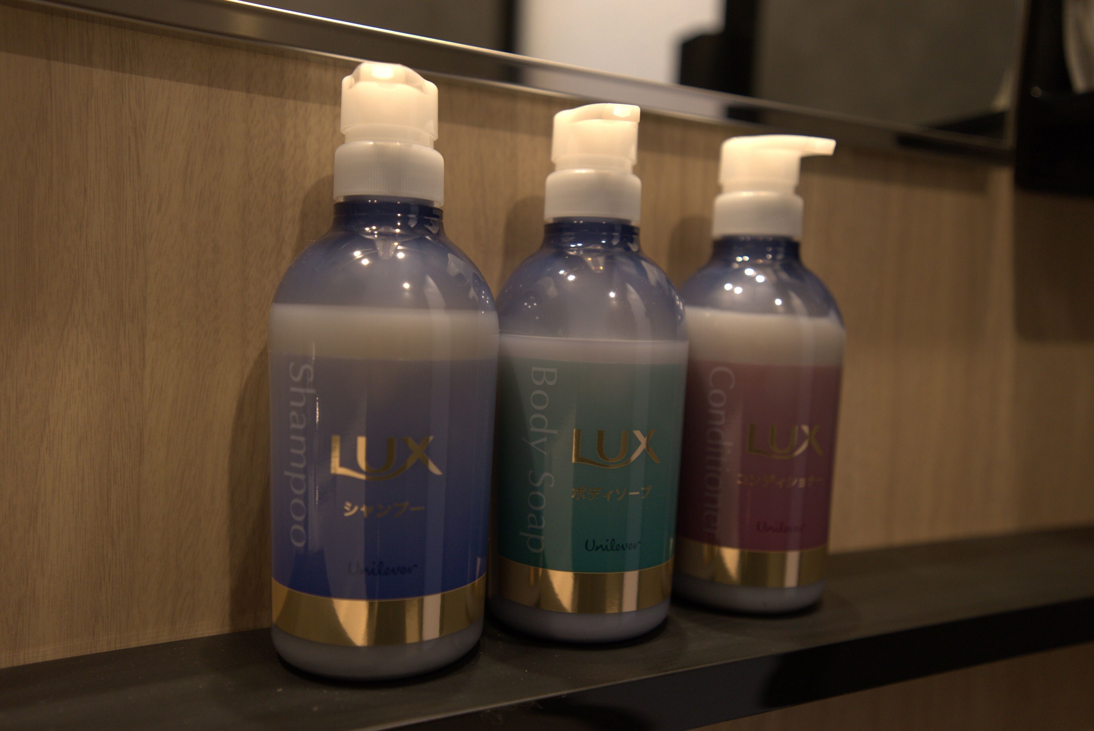 Três frascos de shampoo em uma prateleira.