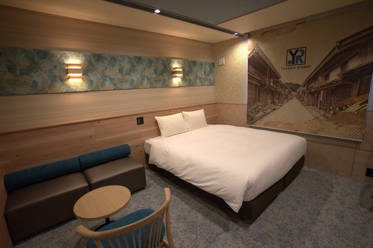 A hotel room with a bed, a sofa, a small table, and a chair.