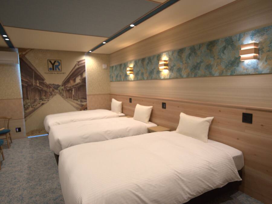A hotel room with two beds, a wooden headboard, a wall mural, and a small seating area.