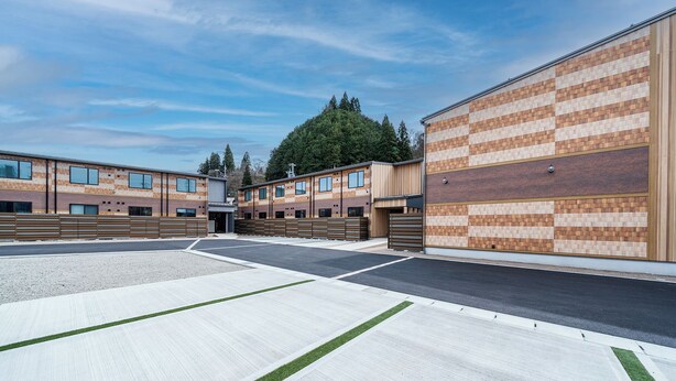 A modern building with a brick facade, large windows, and a parking lot. - YUTORIA RESORT HIDATAKAYAMA (Takayama)