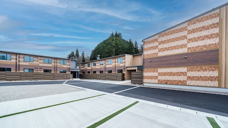 A modern building with a brick facade, large windows, and a parking lot.