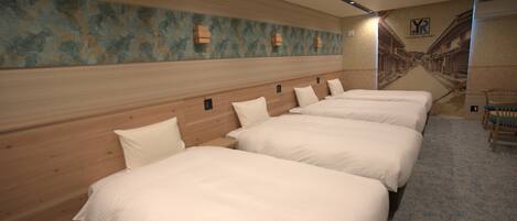 A hotel room with four beds aligned against a wall, a wooden headboard, and a mural depicting a street scene.