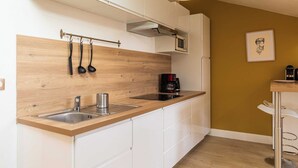 A modern kitchen with a wooden backsplash, stainless steel sink, and a coffee maker. - DIFY Reinach - Jean Macé (Lyon)