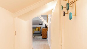 A hallway leading to a living area with a sofa and a wooden cabinet. - DIFY Reinach - Jean Macé (Lyon)
