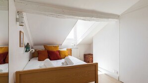 A bedroom with a sloped ceiling, a wooden bed, and a skylight. - DIFY Reinach - Jean Macé (Lyon)