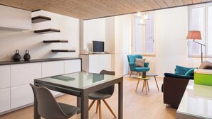 Een moderne keuken met inbouwplanken, een eethoek met een glazen tafel, en een gezellige zithoek met een bank en fauteuil.