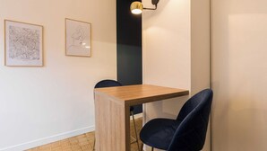 A dining area with a wooden table and two dark chairs, a black accent wall, and two framed artworks on the wall. - DIFY Charme - Bord du Rhône (Lyon)