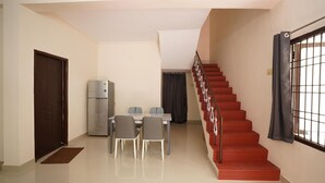 Ein Essbereich mit Tisch und Stühlen, einem Kühlschrank und einer Treppe mit Geländer.