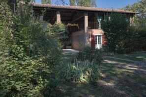 Un edificio rústico con tejado de baldosas, rodeado de abundante vegetación.