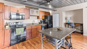 A modern kitchen with wooden cabinets, stainless steel appliances, and a granite countertop.